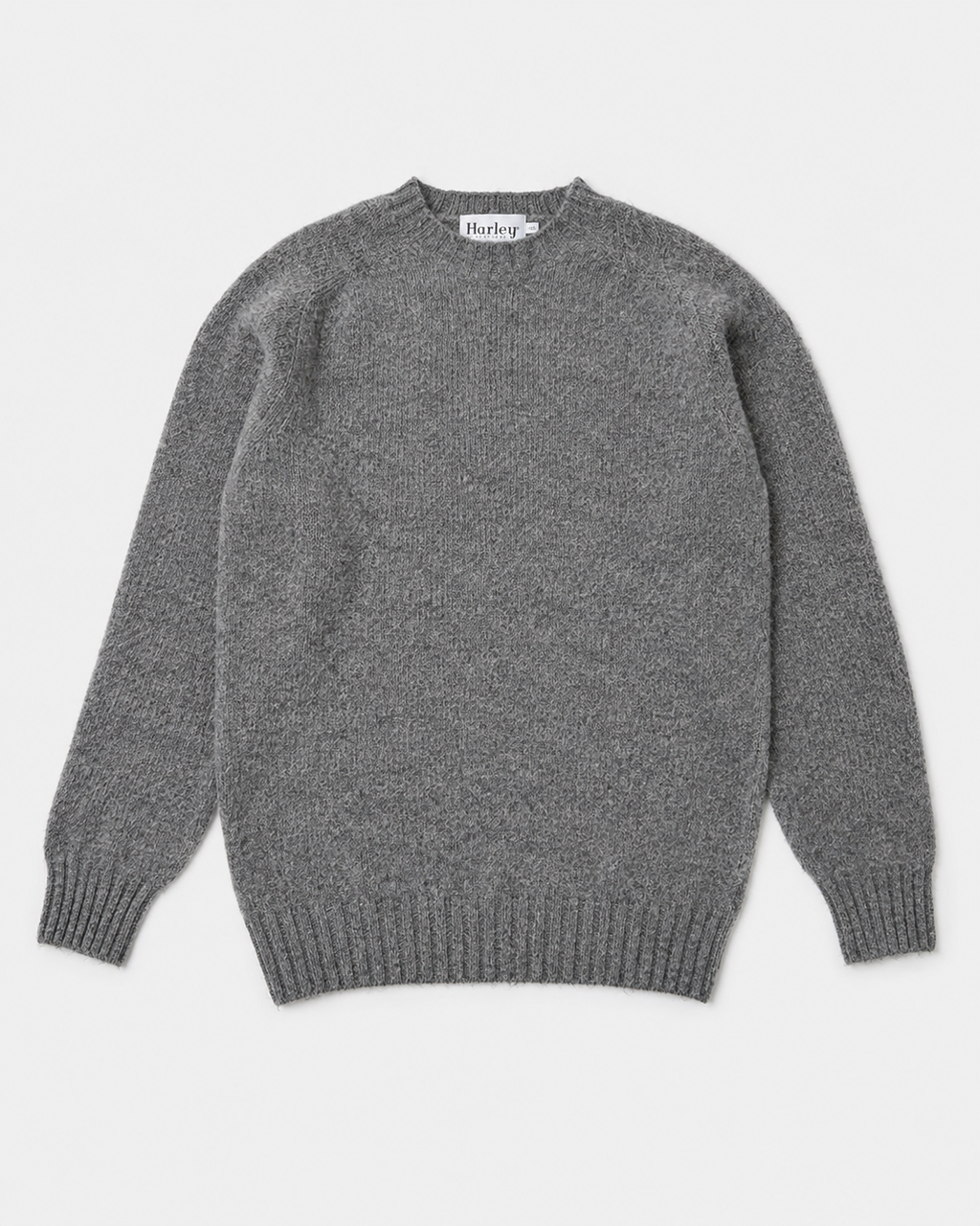 A classic gray knit crewneck sweater with ribbed cuffs and hem, laid flat against a light gray background. The brand name 'Harris' is visible on the inner neck label.